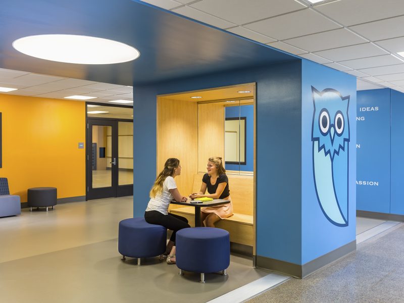 Two girls sitting on built-in bench in gathering area of school