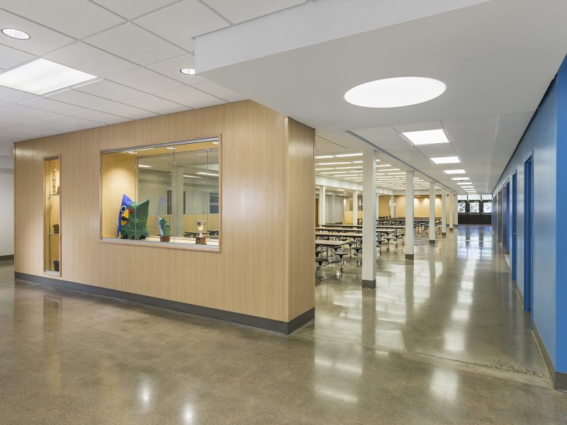 Entrance to school lunchroom with wood cabinet and display case used as separating wall