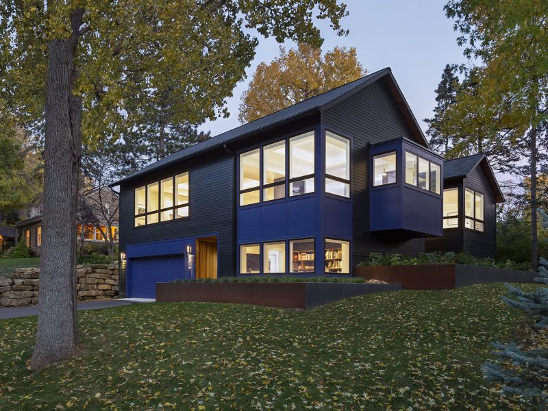 Dusk view of modern home that is painted black with vibrant blue details